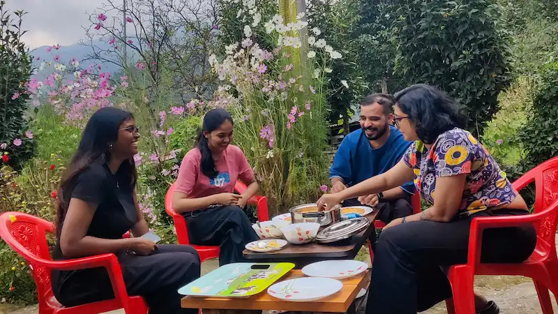 Travelers enjoying a homemade breakfast at a Shergaon homestay, surrounded by flowers.