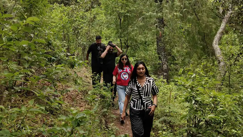 A group hiking through dense forest on the trail to Choskorong Waterfall.