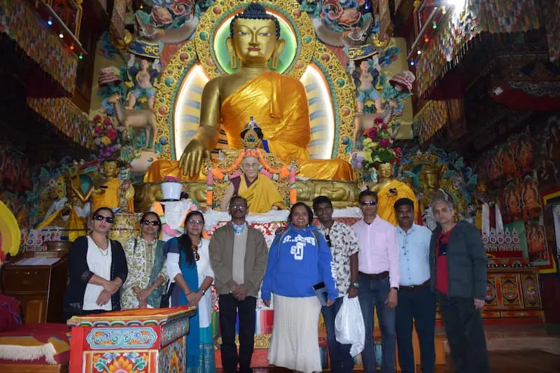A group of visitors inside Tawang Monastery in front of the large gilded Buddha statue