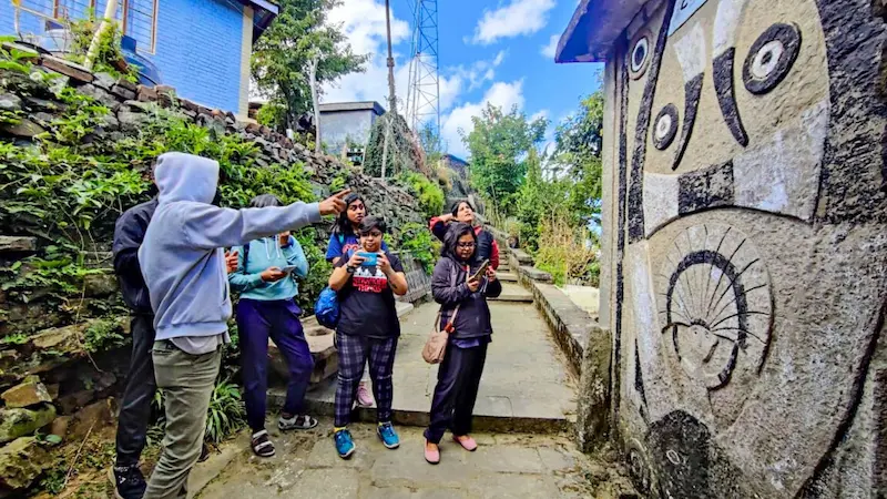 A group of travelers looking at the carved stone artwork on a wall near Khonoma's entrance gate.