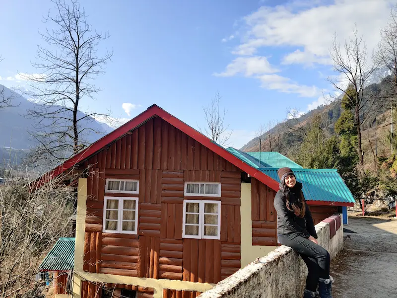 A traditional wooden cottage homestay in Lachung, North Sikkim, with mountains in the background.